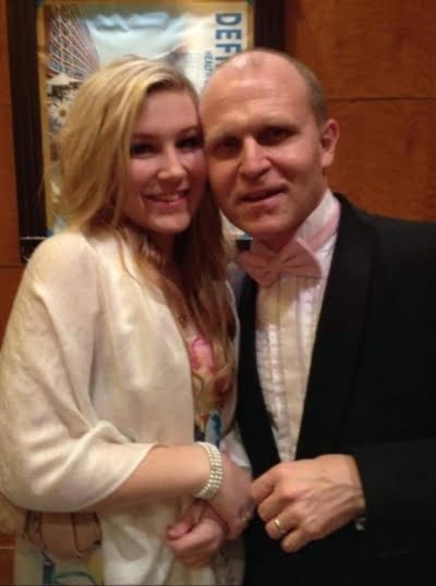 Molly and her dad Andy, Molly is wearing a cream shawl and her dad a black jacket, pink bow tie and white shirt. both looking at the camera smiling.